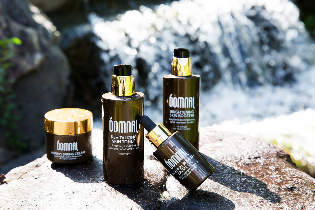 High-end skincare products showcased by a natural waterfall for a refreshing appeal.